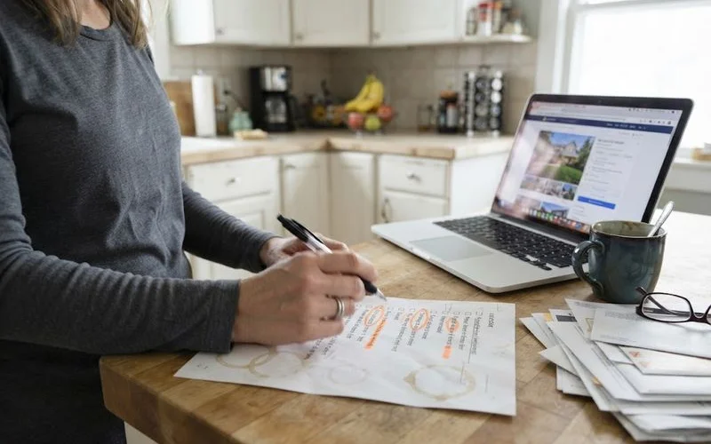 A checklist on a clipboard with several items circled in red, next to a rent-to-own contract and a pen